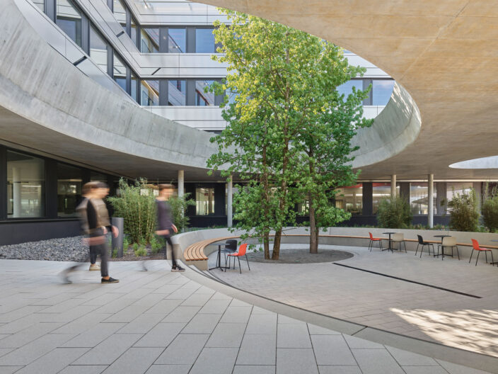 2022_B14_Bilddarstellung-4_Foto_Zooey-Braun Außenperspektive organischer Innenhof mit mittig gepflanzten Bäumen der Firmenzentrale Schweickert