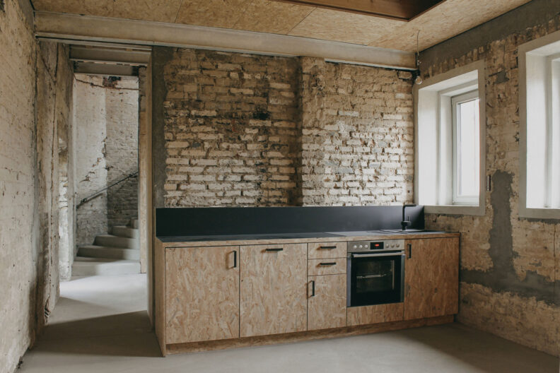 2022_B15_A-Z-Architekten_Stellwerk_Innenansicht1 Innenperspektive Küchenzeile in Rohbau anmutendem Innenraum mit kahlen Klinkerwänden des Kinder- und Jugendtreffs im ehemaligen Stellwerk