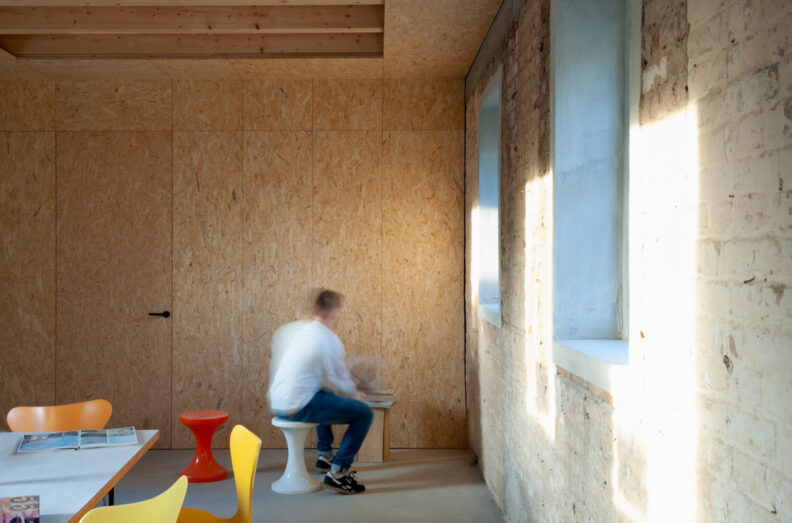 2022_B15_A-Z-Architekten_Stellwerk_Innenansicht3 Innenperspektive Aufenthaltsraum mit OSB Wänden und kahlen Klinkerwänden des Kinder- und Jugendtreffs im ehemaligen Stellwerk