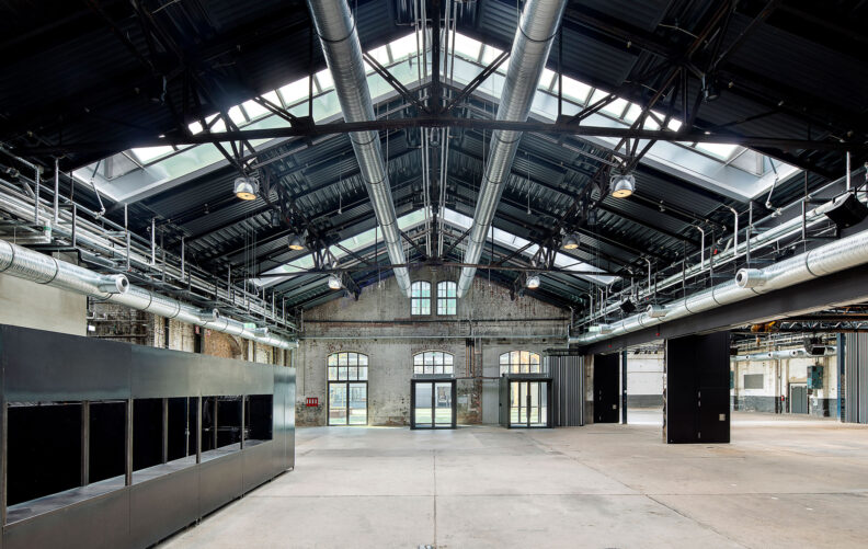 2022_B26_03-Wagenhallen-Stuttgart-Daniel-Stauch Innenraumperspektive Eingangsbereich des Hallenraums mit eingestellten Funktionskuben und flexibler Trennwand zur 4-Teilung der Wagenhallen Stuttgart